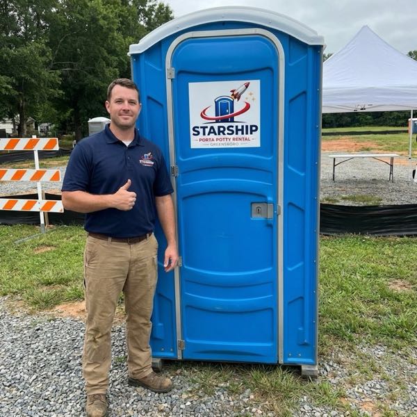 Starship team with portable restroom at outdoor event