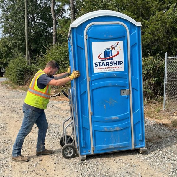 Worker moving porta potty at outdoor event